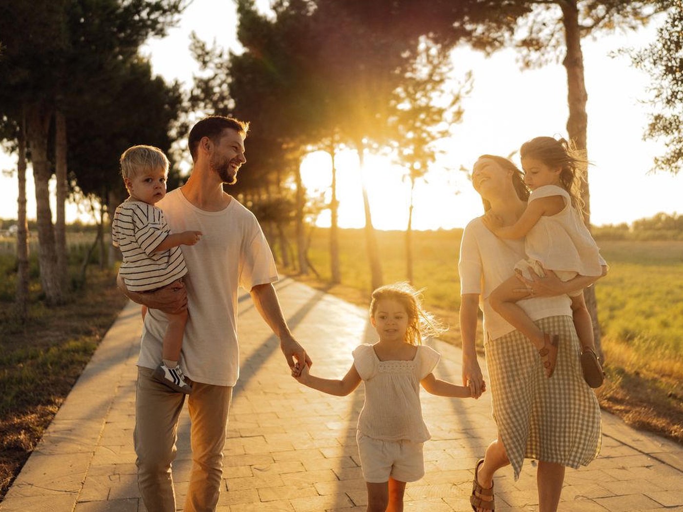 A mum, dad and three children walking together on a sunlit path