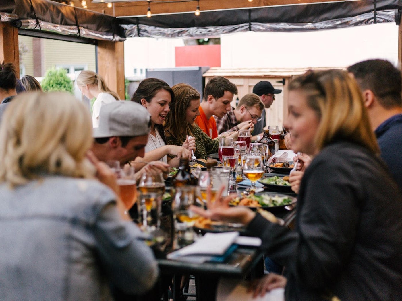 A big group of friends around a long table with drinks and food
